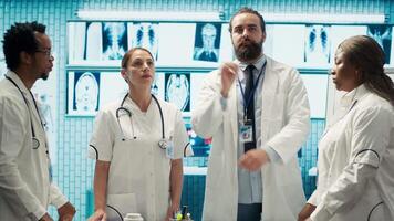 Doctor specialists reviewing human anatomy scans via hologram projection in cabinet, ensuring effective treatment plans. Team of healthcare experts use augmented visualization. Camera A. video