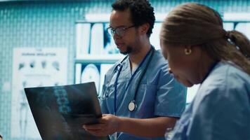 Physicians and radiologists analyzing x ray scans to create an effective treatment plan. Medics doing teamwork at a private clinic to ensure radiography based diagnostics for healthcare. Camera A. video