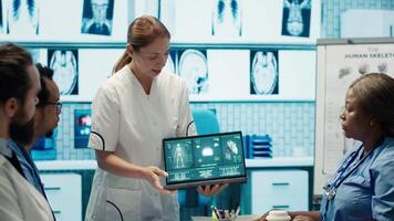 Diverse medical team examining test results and discussing innovative treatment plans at a modern clinic to enhance patient care quality. Doctors and nurses review x ray scans. Camera A. video