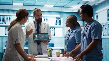 Professional medic analyzing mri brain scan with his staff in medical office, neuroscientist examining tomography with diverse doctors. Experts in neuroscience at treatment center. Camera B. video