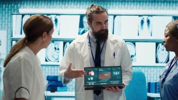 Professional medic analyzing mri brain scan with his staff in medical office, neuroscientist examining tomography with diverse doctors. Experts in neuroscience at treatment center. Camera A. video