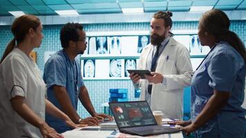 Neurology specialist examines magnetic resonance imaging brain scan with team during a meeting, looking at tomography for accurate neuroscience diagnosis. Diverse team of doctors. Camera B. video