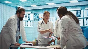 Group of healthcare workers analyzing diagnostic data and planning treatment in a private clinic, emphasizing collaboration. Coordinating recovery plans after recent test results. Camera B. video