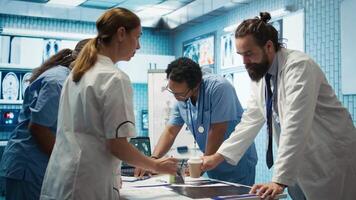 Medic discuss human anatomy scans in a radiology diagnostic meeting at a treatment center, expertise in analyzing x ray results. Doctors examine hospital records and analytics. Camera B. video