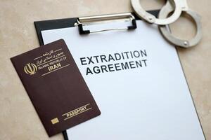 Passport of Iran and Extradition Agreement with handcuffs on table photo