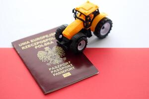 Red polish passport and yellow tractor on smooth red and white flag of Poland photo