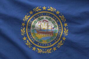 New Hampshire US state flag depicted on folded wavy fabric of old cloth photo