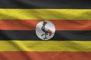 Uganda flag depicted on folded wavy fabric of old cloth photo