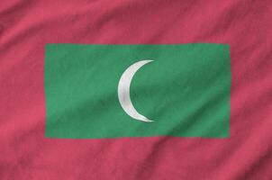 Maldives flag depicted on folded wavy fabric of old cloth photo