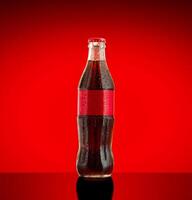 Cola soft drink in a glass bottle on red Background. photo