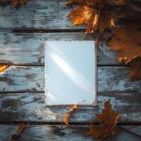 Blank notepad surrounded by autumn leaves on a rustic wooden table in late afternoon light photo