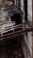 Ruined building. Old architecture with broken windows and many holes in the walls. Exterior of damaged enterprise during military action. Close-up. Vertical video