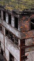 Ruined architecture after military actions. Abandoned building with broken windows and many hole in walls. Damaged building outdoors. Aerial view. Vertical video
