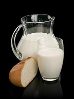 Piece of a white loaf and glassware filled with milk photo