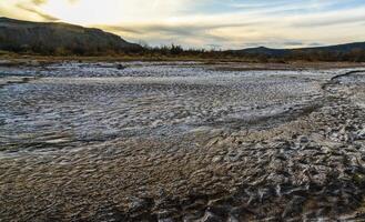 Cracked red clay and white salt on the surface in a dried riverbed in the desert of New Mexico, USA photo