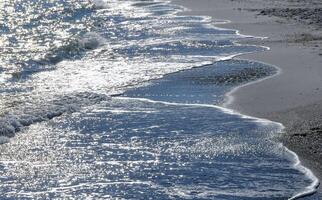 Bright reflections on the water on a sunny day on the sandy shore of the Black Sea photo