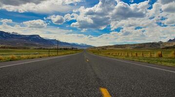 The landscape is in the wild. A road going into the distance, white clouds on the horizon. photo
