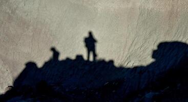 Shadow of a man against a background of dry cracked clay, cracks on the ground. photo