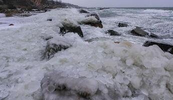 Frozen Black Sea, ice-covered and frozen coastal rocks in the piers, harsh winter photo