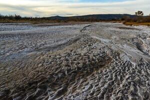 Cracked red clay and white salt on the surface in a dried riverbed in the desert of New Mexico, USA photo