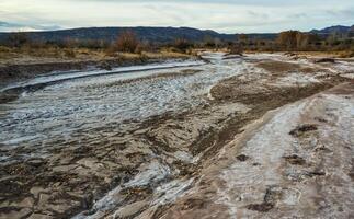 Cracked red clay and white salt on the surface in a dried riverbed in the desert of New Mexico, USA photo