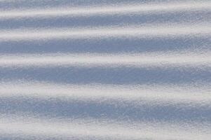 Snow lies in waves in a cold snowy winter, the play of light in straight lines photo