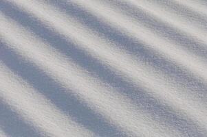 Snow lies in waves in a cold snowy winter, the play of light in straight lines photo