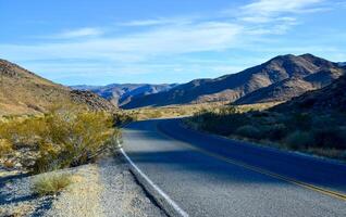 Empty asphalt road in the desert, Mountains in the background in Joshua Tree National Park photo