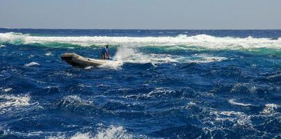 Rubber boat with sailor on mooring rope to Big Brother island of diving yacht during a storm, Red Sea photo
