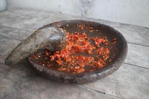 Sambal cobek or traditional Indonesian chili sauce, made from chilies, spices and other kitchen spices. made using a stone mortar and pestle. suitable for menu books. photo