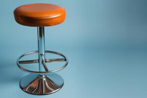 A stylish orange bar stool against a soft blue backdrop in a modern studio setting photo