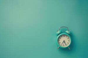 A vintage alarm clock rests against a soft turquoise background, its hands pointing to early morning light photo