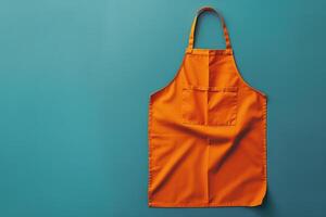 Bright orange apron hanging against a teal backdrop in a kitchen setting, ready for culinary adventures photo