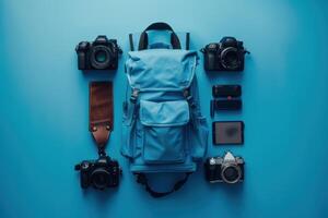 A vibrant blue backdrop showcasing a stylish backpack surrounded by various cameras and accessories for the aspiring photographer photo