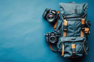 A creative flat lay of a stylish backpack and camera gear against a vibrant blue backdrop photo