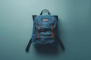 A stylish blue backpack resting on a smooth teal surface, showcasing its unique straps and texture, perfect for everyday adventures and travel photo