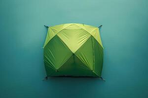 A vibrant green tent pitched against a tranquil blue backdrop in a serene outdoor setting, inviting adventure and relaxation at dawn photo