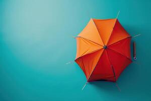 Bright orange umbrella resting against a teal wall, capturing the essence of color contrast and minimalism in a stylish indoor setting photo