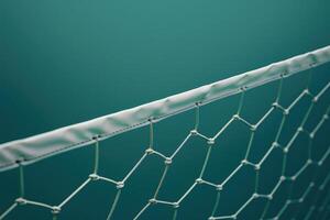 A close-up view of a sports net against a turquoise background with intricate hexagonal patterns and soft lighting photo