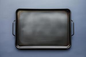 Shiny baking tray resting on a dark surface illuminated by soft light photo
