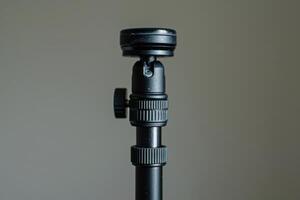 Close-up of a sturdy black tripod head showcasing intricate adjustments in a minimalistic setting photo