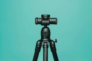 A sleek black tripod with a camera positioned against a vibrant turquoise backdrop, showcasing the perfect blend of technology and art photo