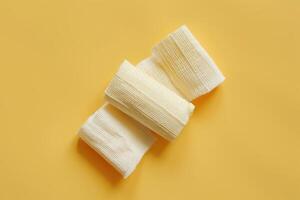 Soft cotton bandages on a vibrant yellow surface creating a soothing contrast in a minimalistic and artistic display photo