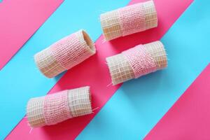 Crafting with texture colorful fabric wrapped rolls on vibrant pink and blue backdrop photo