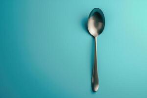 A sleek silver spoon resting against a vibrant turquoise backdrop, highlighting simplicity and elegance in everyday objects photo