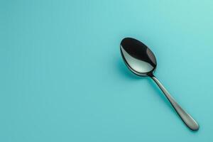 A sleek stainless steel spoon resting on a vibrant turquoise background photo