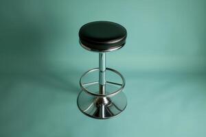 A sleek black bar stool stands elegantly against a calming turquoise backdrop, inviting relaxation in a modern setting photo