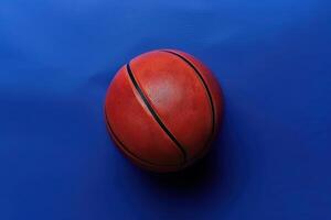 A vibrant orange basketball resting on a blue surface, ready for play in a dynamic sports environment photo