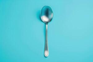 A shiny spoon rests on a vibrant turquoise background, reflecting soft light photo