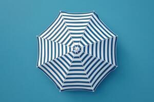 A vibrant blue and white striped umbrella rests against a solid blue background, evoking summertime relaxation and beach days photo